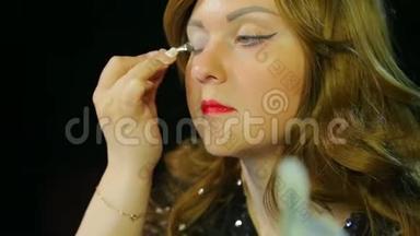 化妆室里的红发女演员用银色的影子做眼妆，准备上台